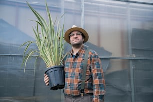 un uomo che indossa un cappello che tiene una pianta in vaso