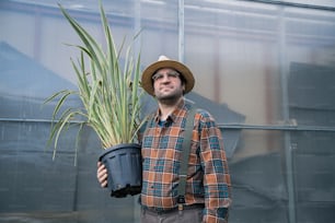 a man wearing a hat holding a potted plant