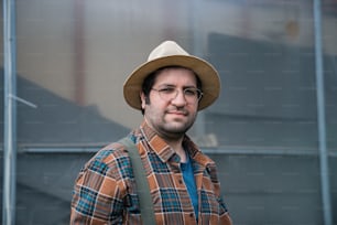 um homem usando um chapéu e óculos em pé na frente de um prédio