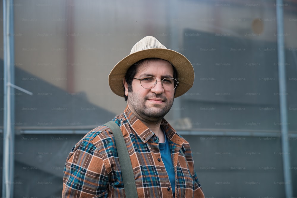 Ein Mann mit Hut und Brille steht vor einem Gebäude