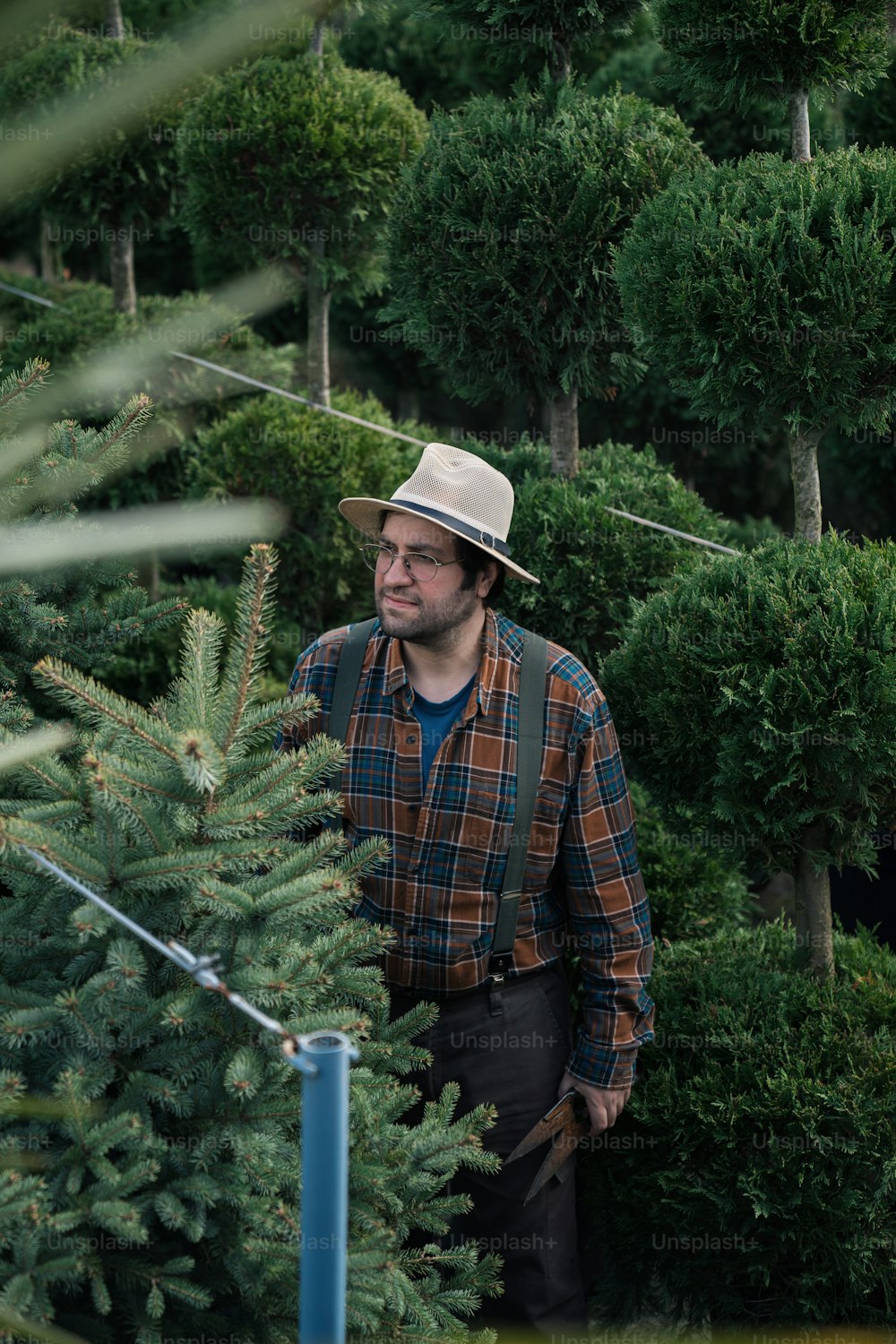 帽子をかぶった男がクリスマスツリーの前に立っている