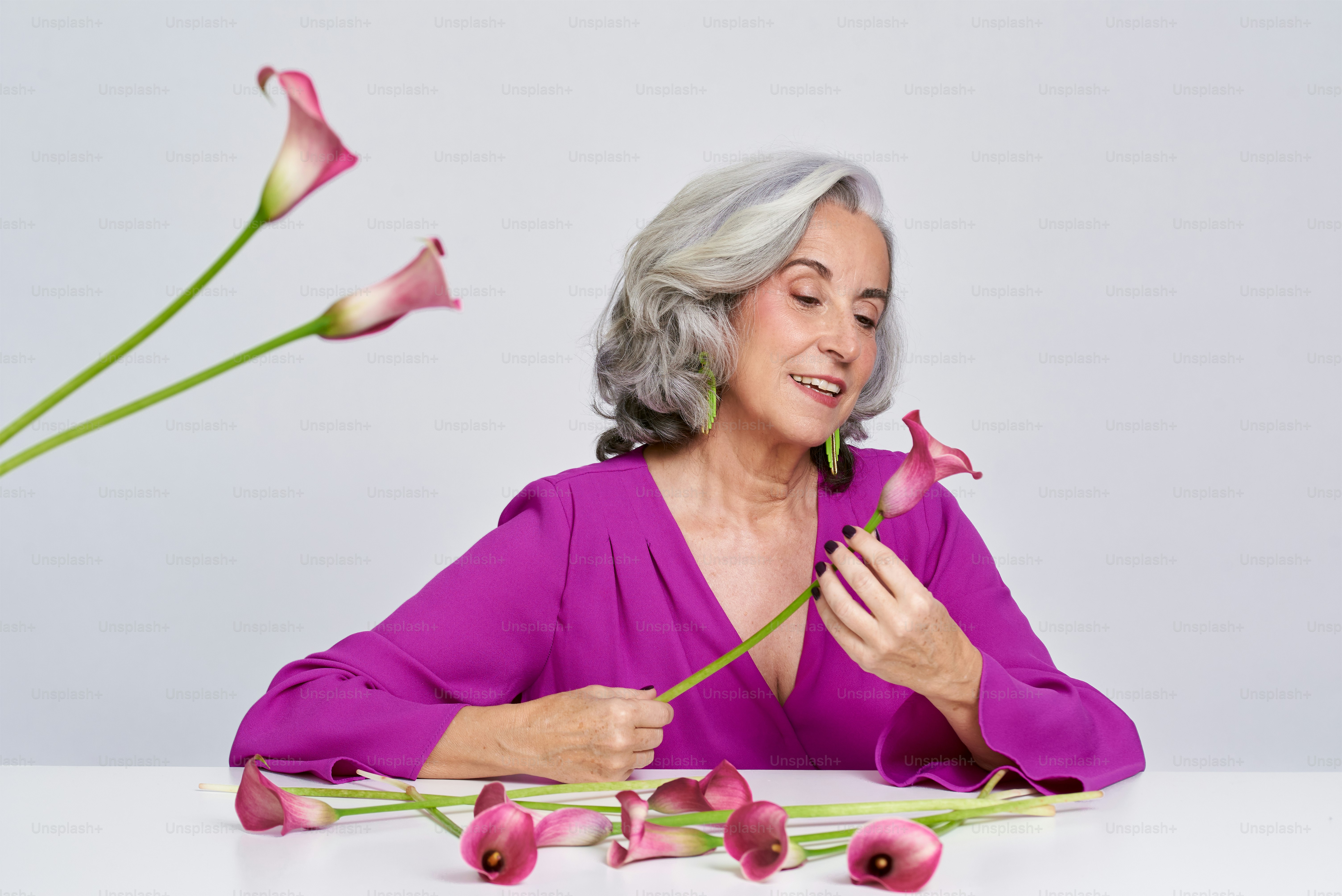 A woman sitting at a table with flowers in front of her photo ...