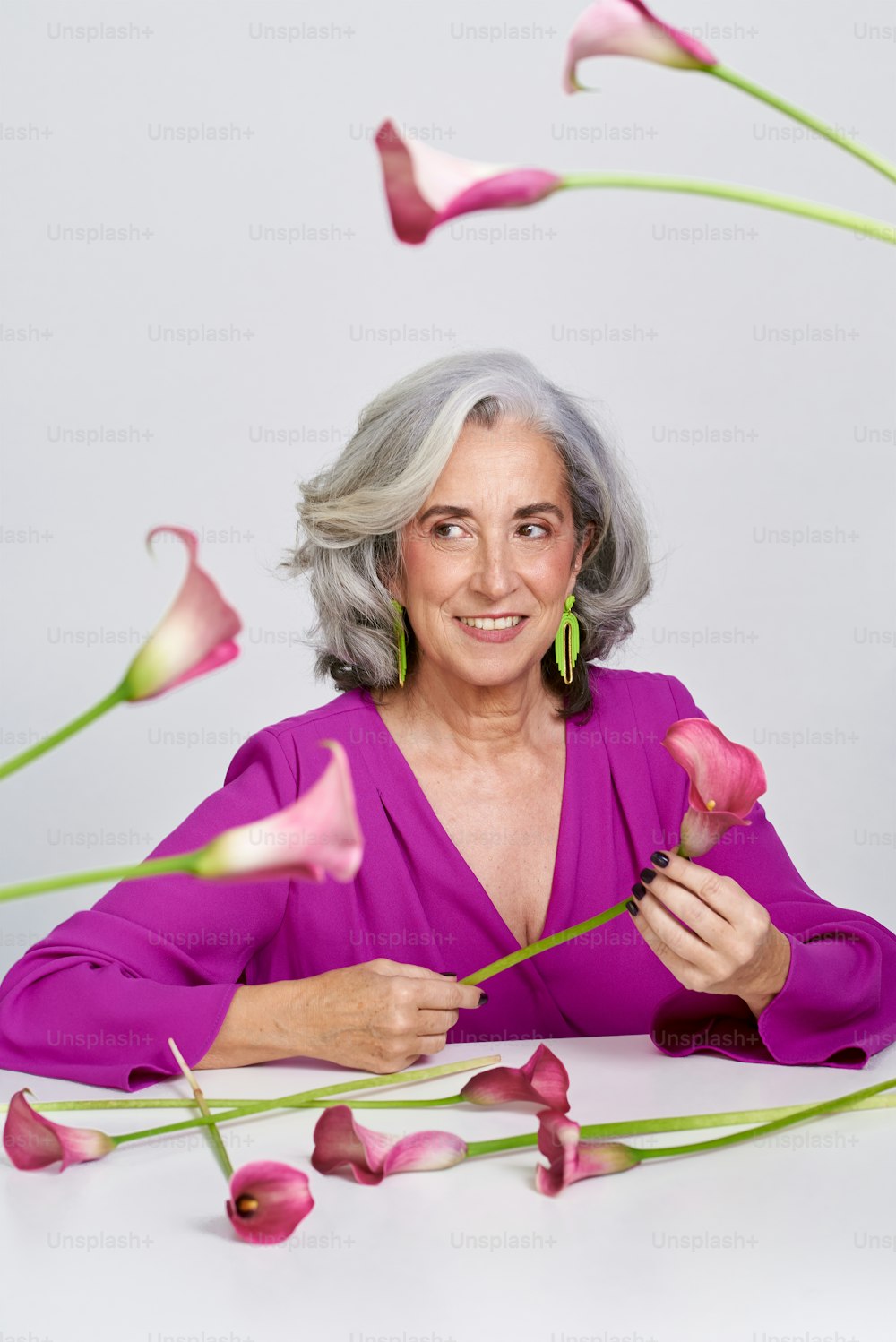 Una donna anziana in un vestito viola che tiene un fiore