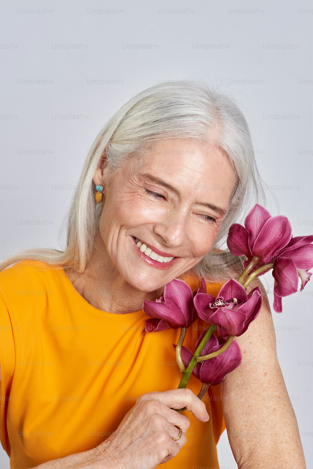 Eine ältere Frau hält einen Strauß lila Blumen in der Hand