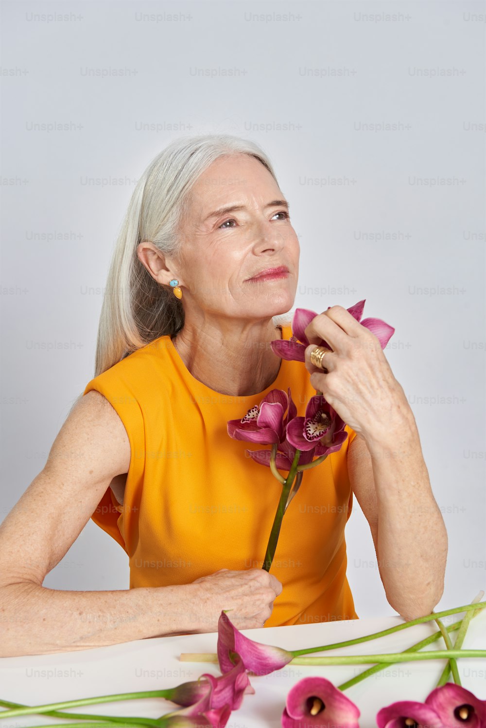 uma mulher sentada em uma mesa com uma flor na mão