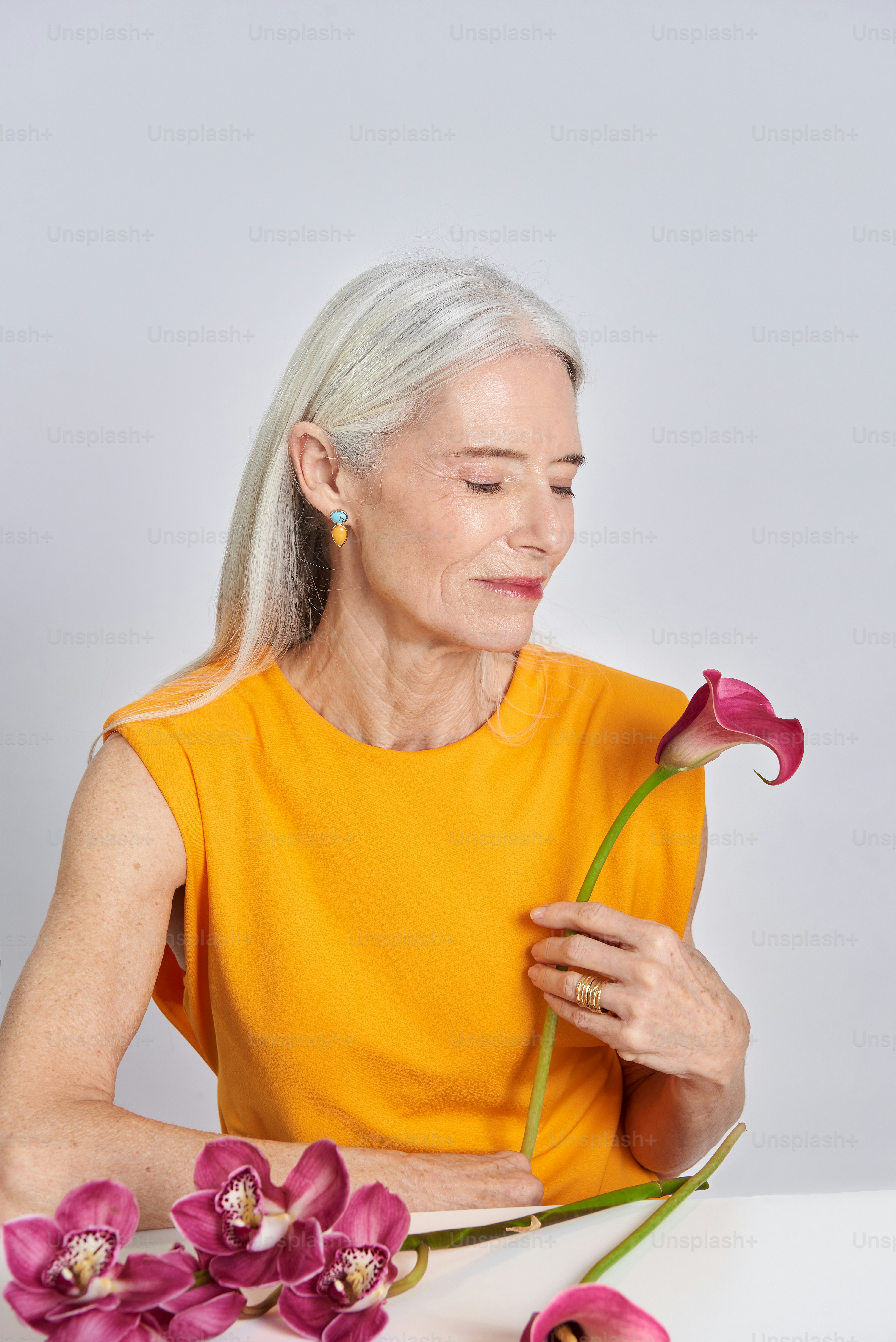 A woman sitting at a table with flowers in front of her photo ...