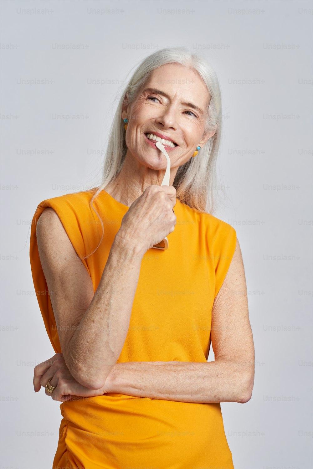an older woman brushing her teeth with an electric toothbrush