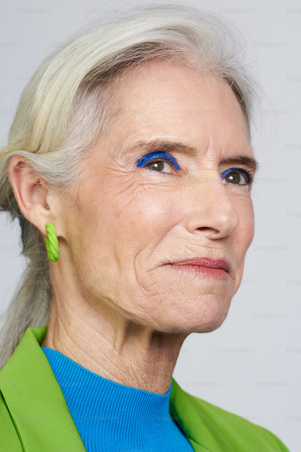 eine Frau mit blauem Eyeliner und grüner Jacke