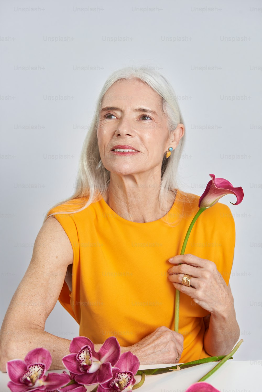 a woman in a yellow shirt holding a flower