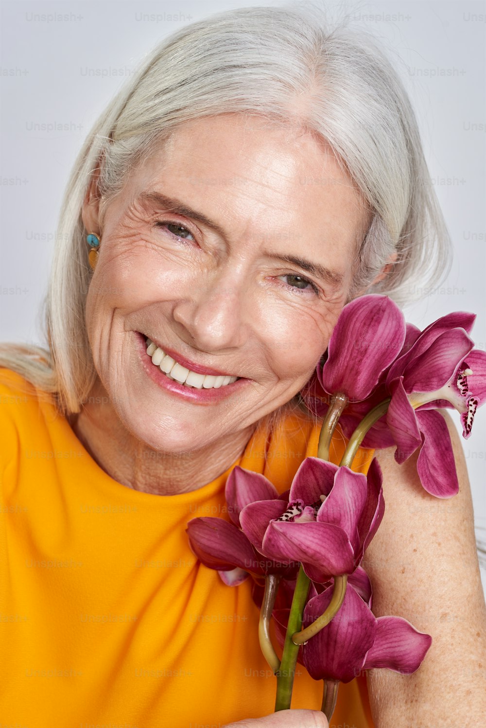 an older woman holding a bunch of purple flowers