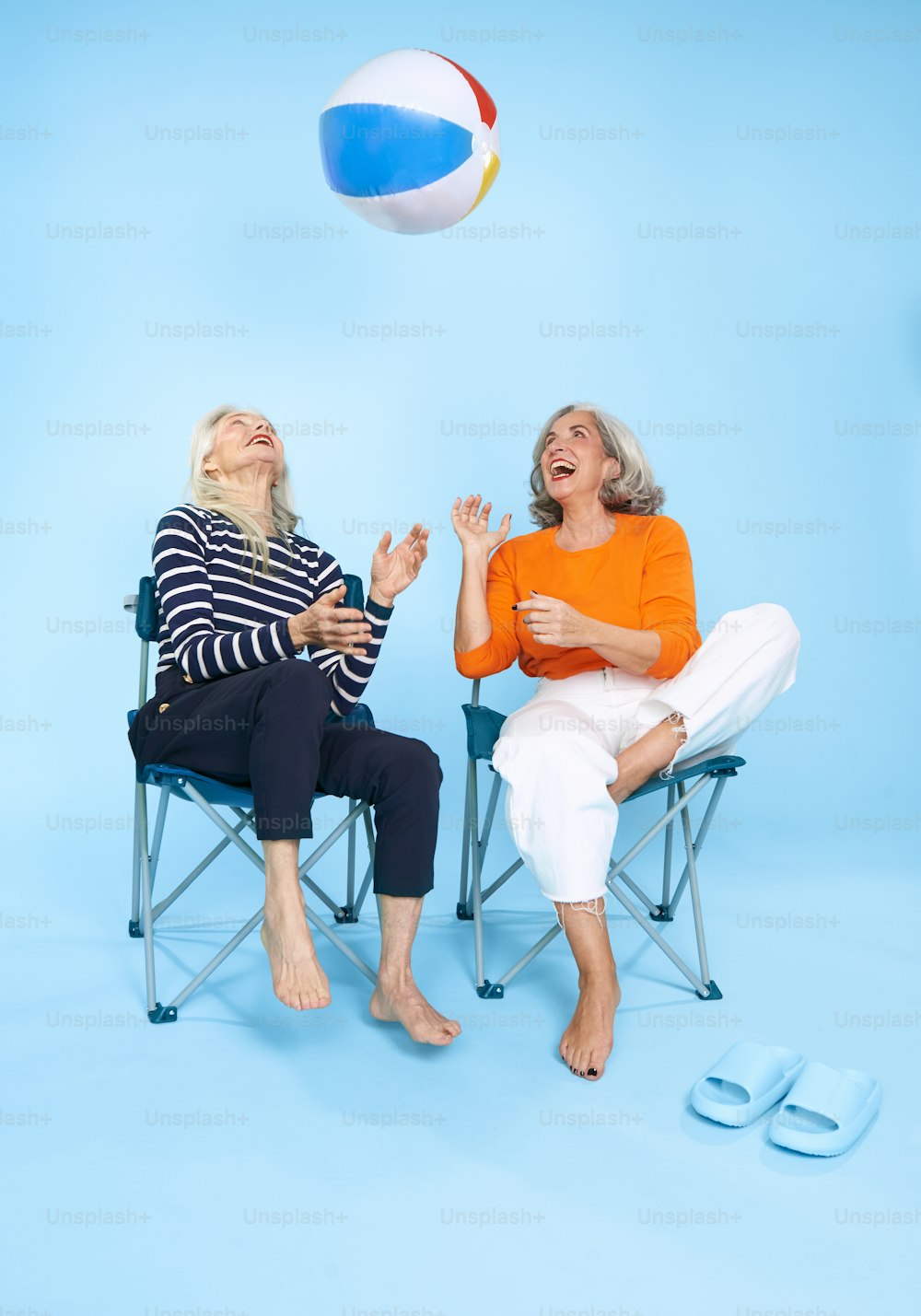 공중에 비치볼을 들고 의자에 앉아 있��는 두 여자
