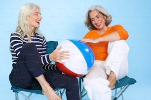 duas mulheres sentadas em uma cadeira com uma bola de praia