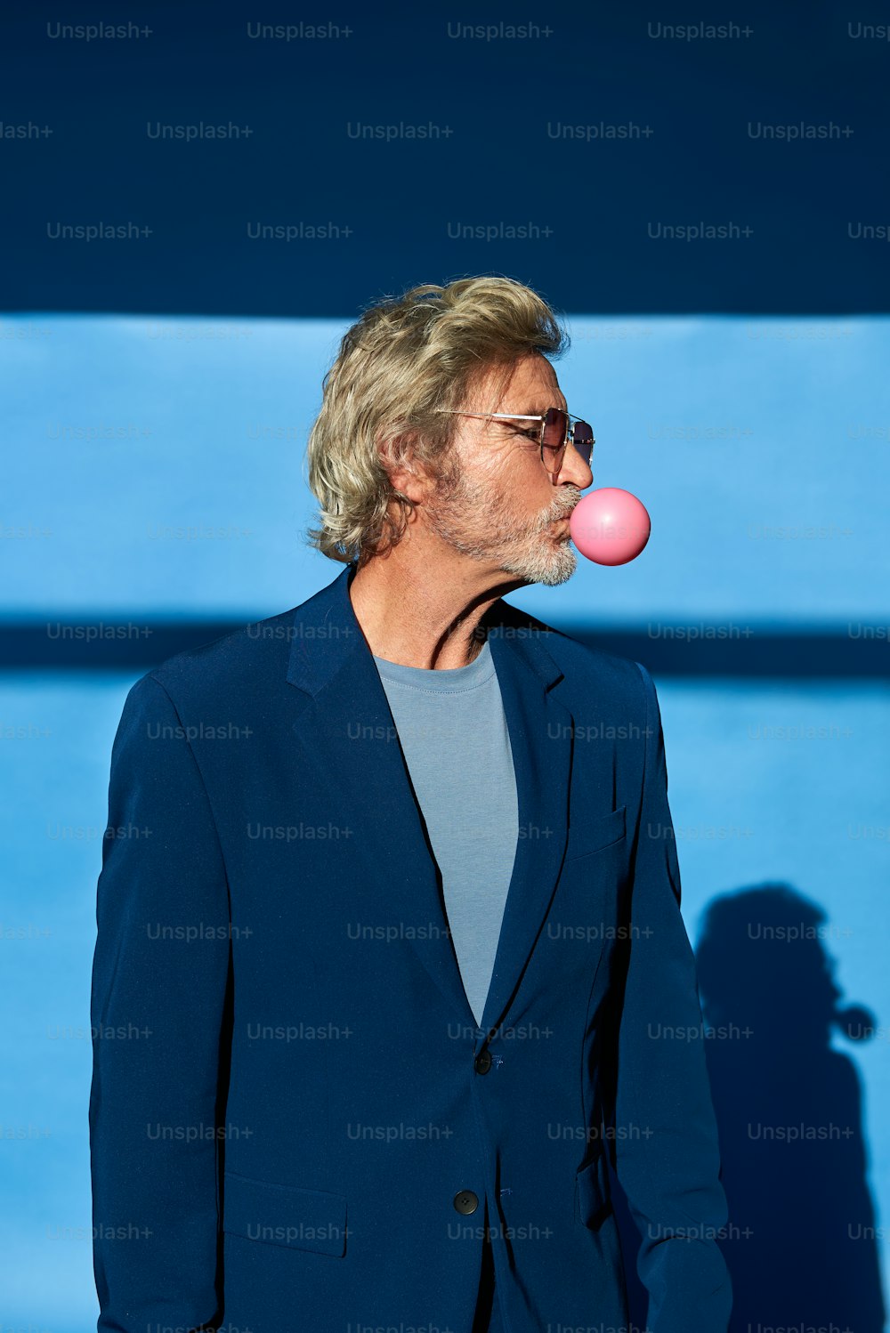 um homem em um terno soprando uma bolha rosa