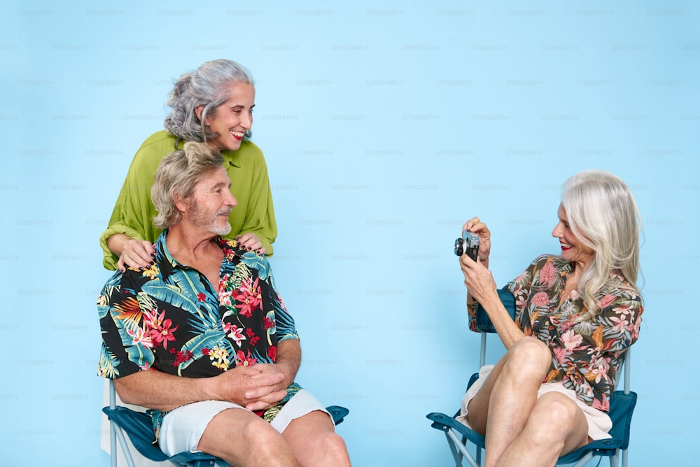 a woman taking a picture of a man sitting on a chair