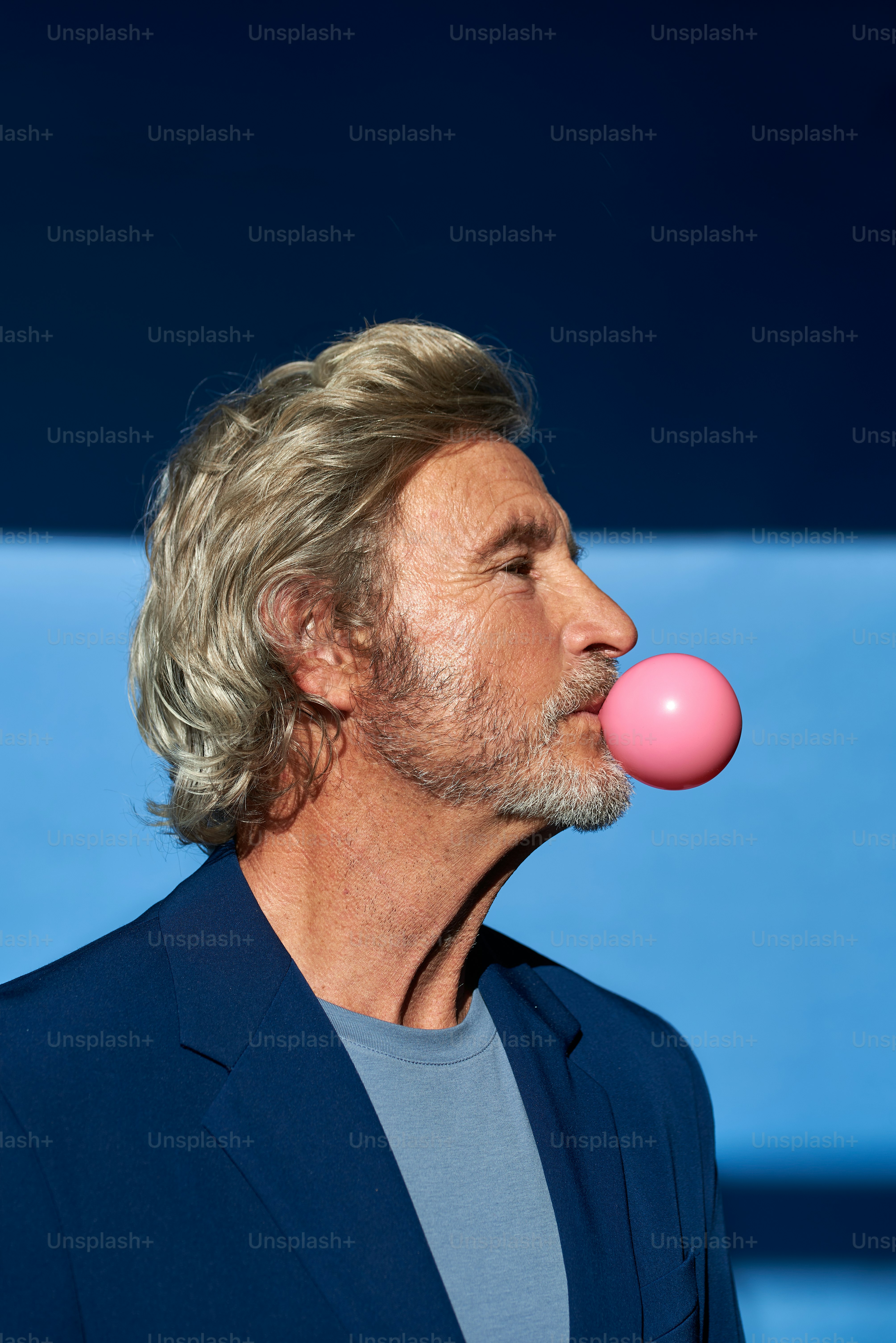 a man blowing a bubble with a pink bubble in his mouth