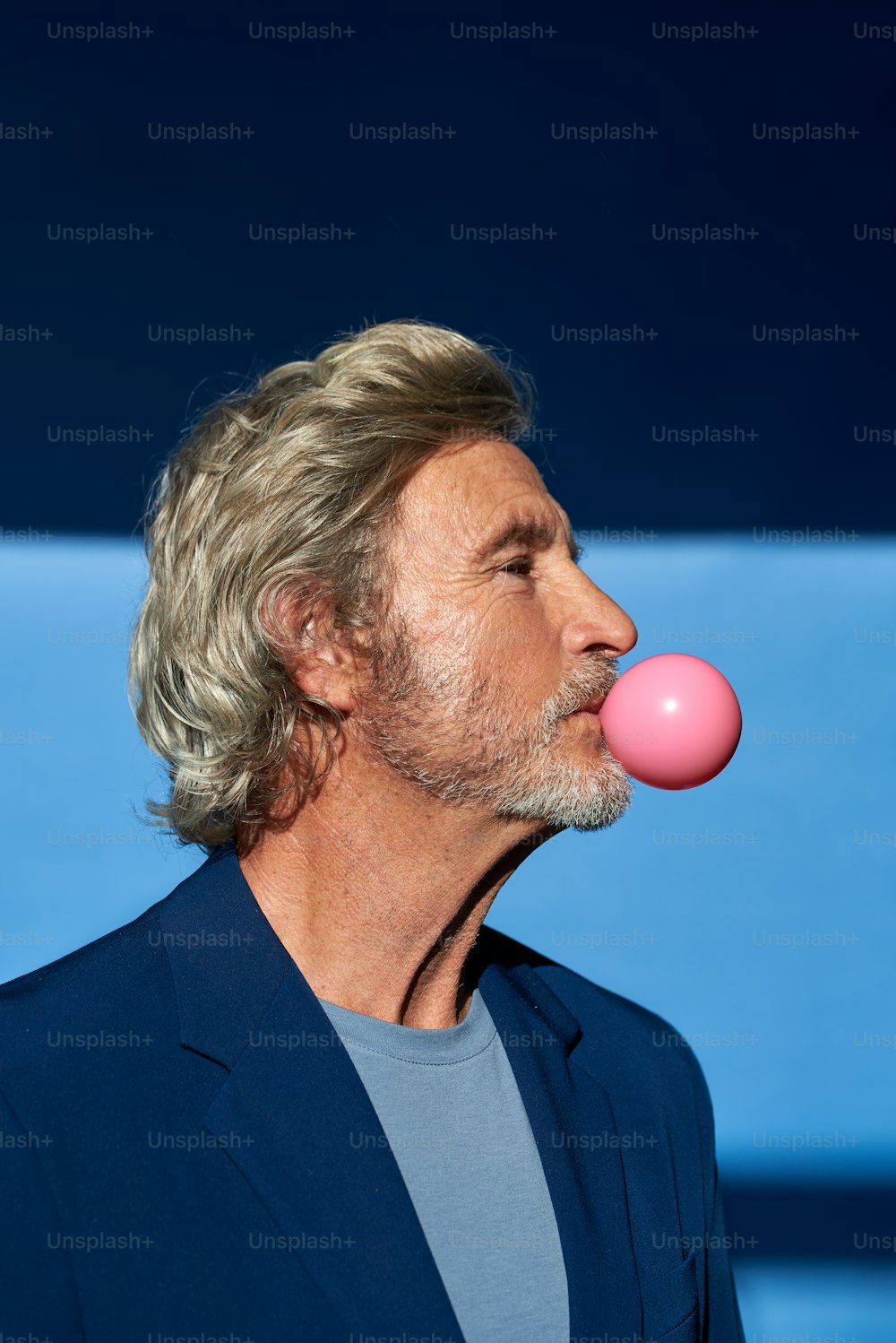 a man blowing a bubble with a pink bubble in his mouth