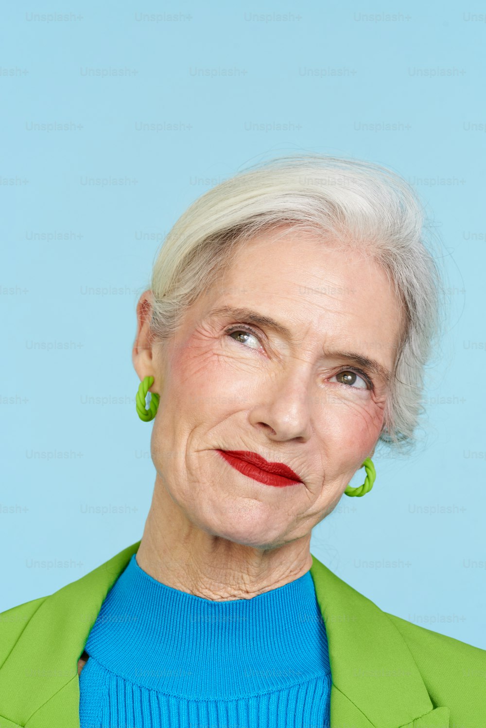 a woman with white hair and green earrings