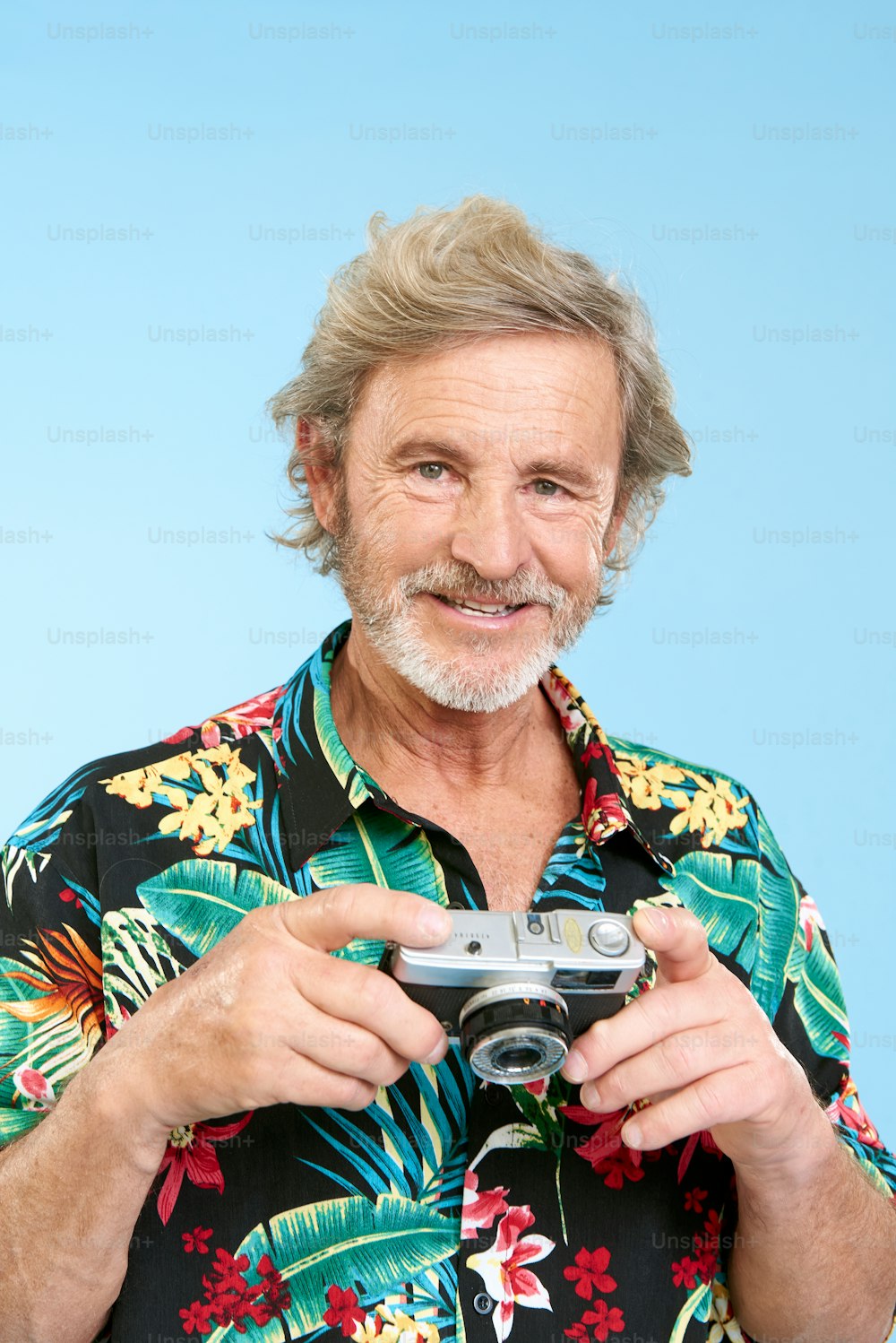 Un uomo in una camicia hawaiana che tiene una macchina fotografica