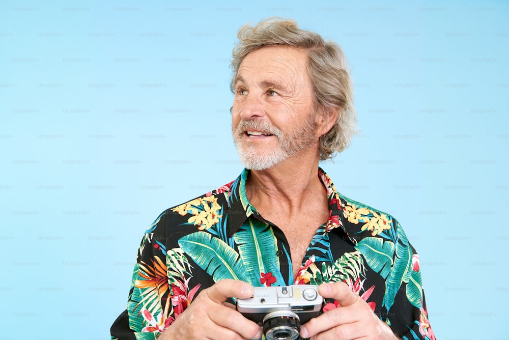 a man holding a camera in front of a blue background