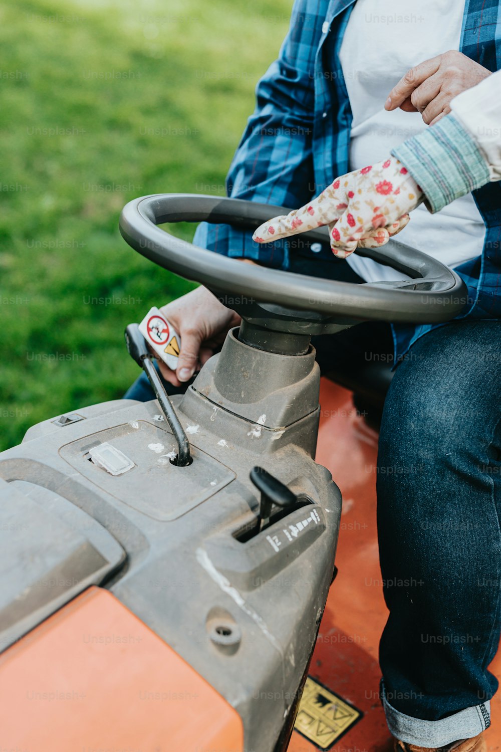 a person sitting on a tractor with a glove on their hand