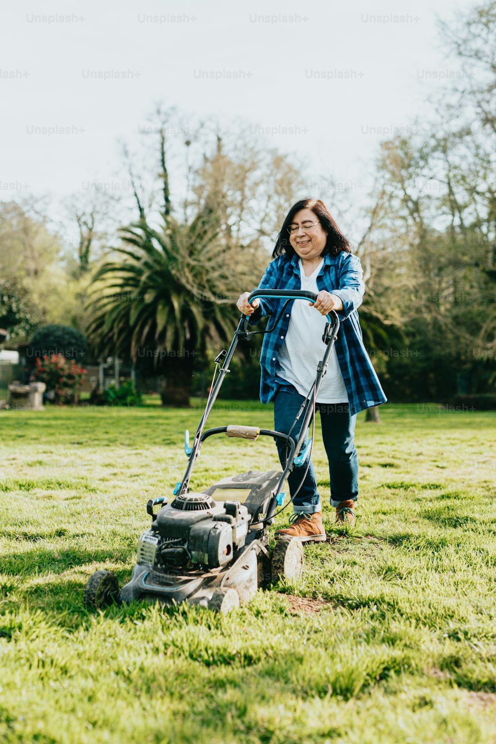 a woman standing in the grass with a lawn mower