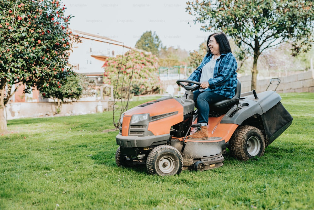 a woman riding on the back of a lawn mower
