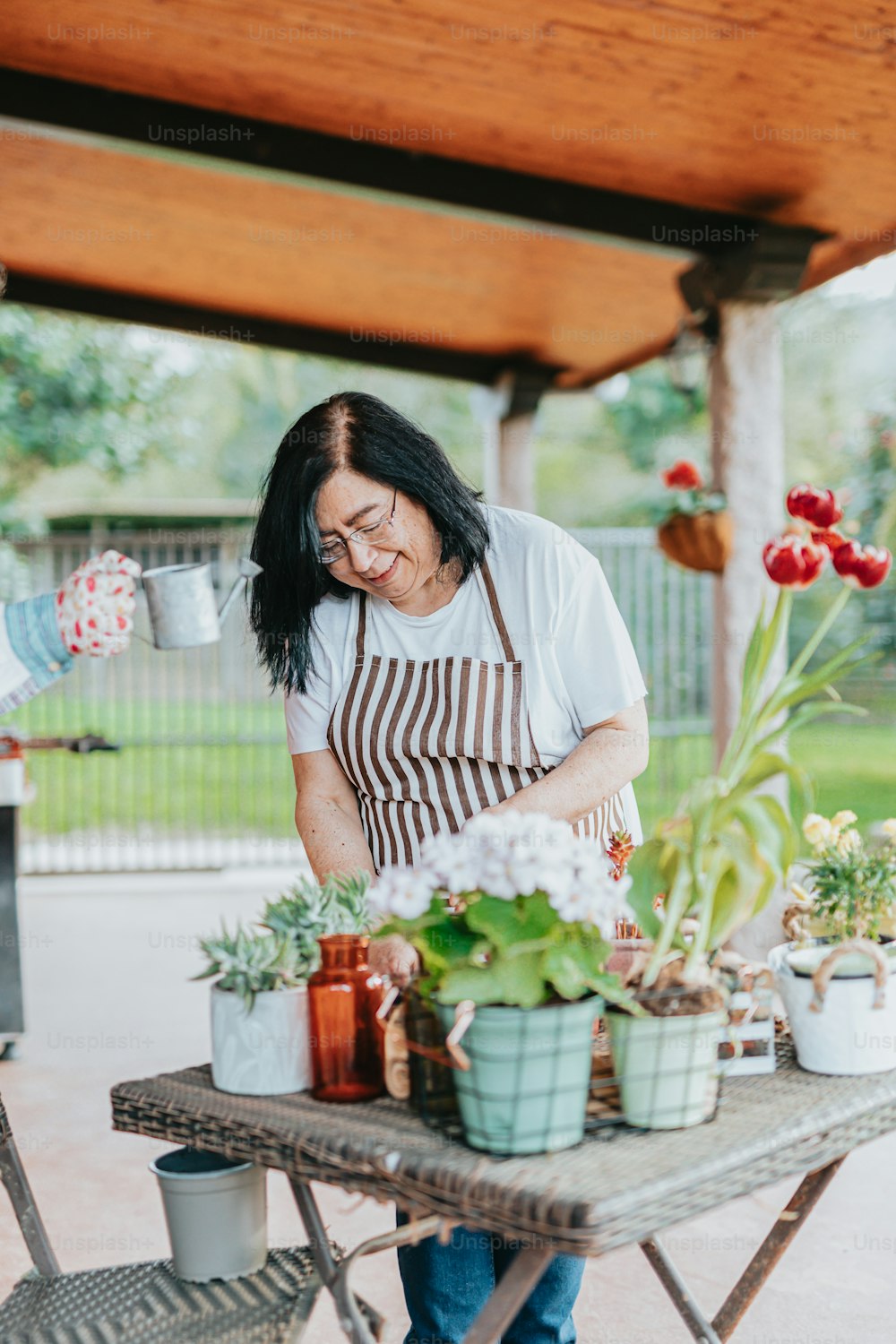 a woman in an apron working on a potted plant