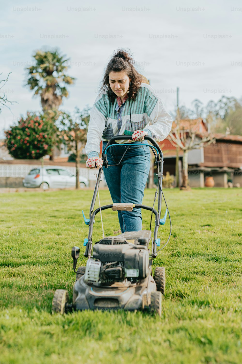a woman mowing the grass with a lawn mower