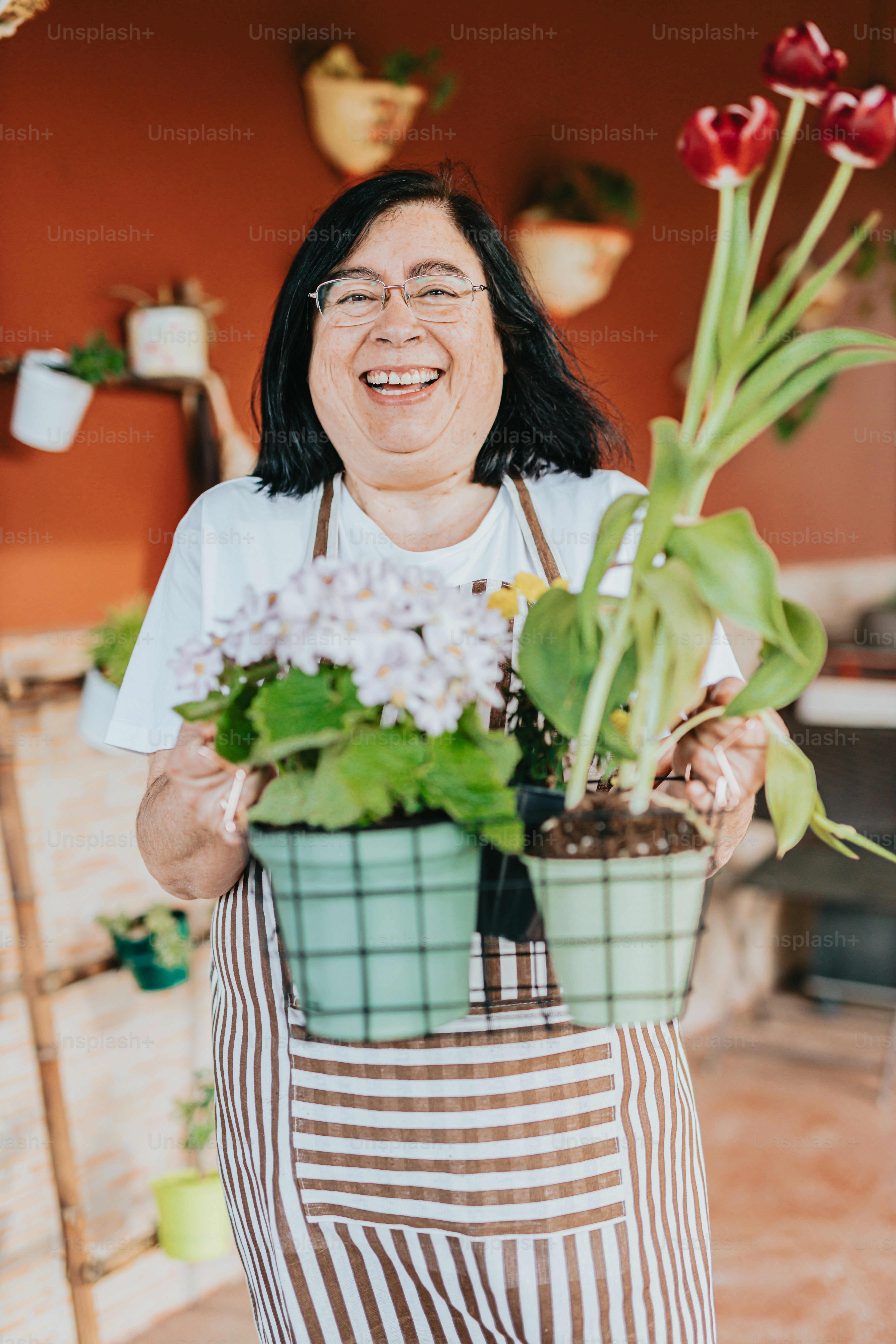 A woman holding a potted plant and smiling photo – Happy face Image on ...