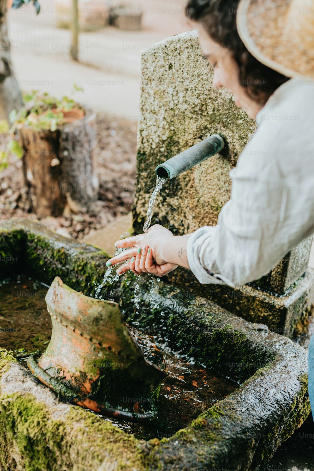 Eine Frau mit Strohhut wäscht sich die Hände