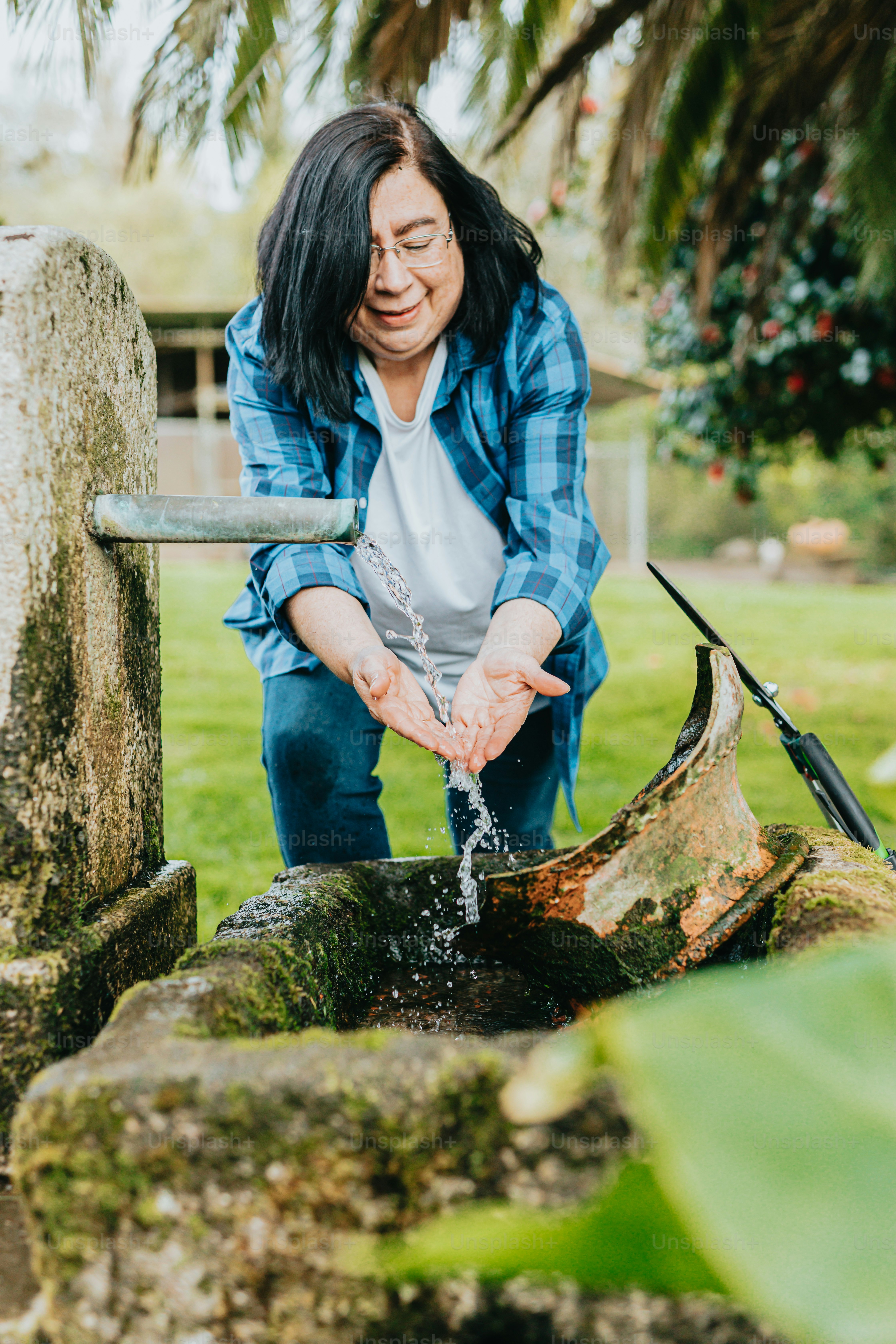 a woman is washing her hands in a stream of water