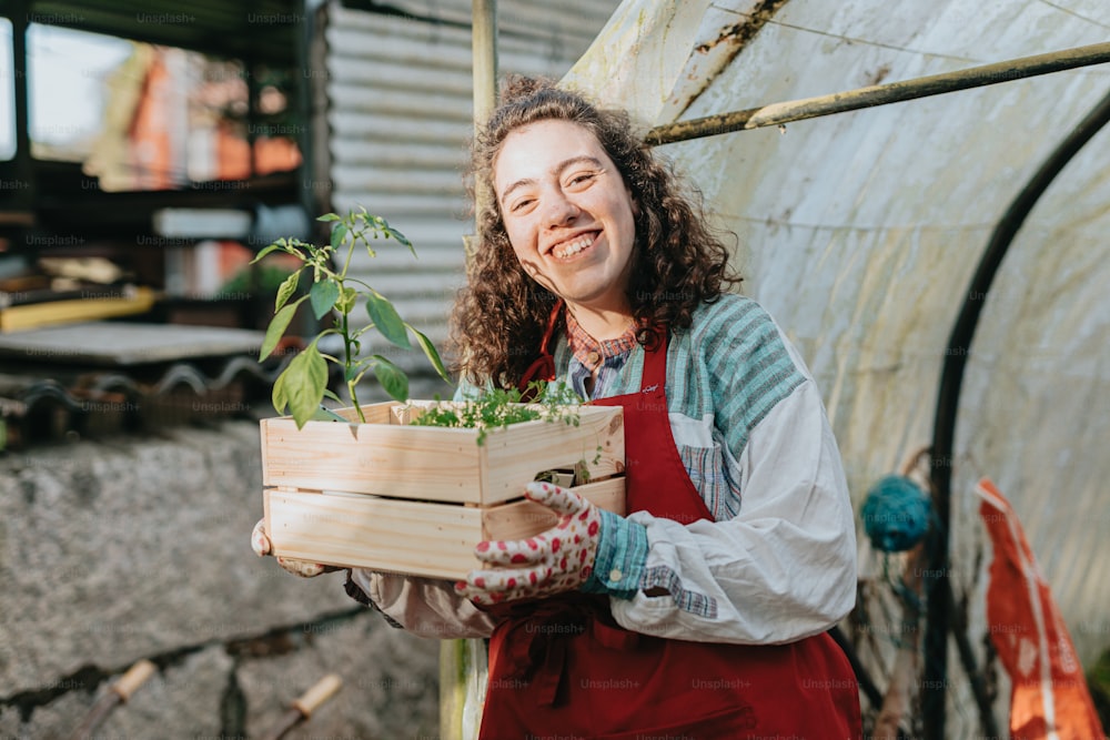 uma mulher em um avental segurando uma caixa de plantas