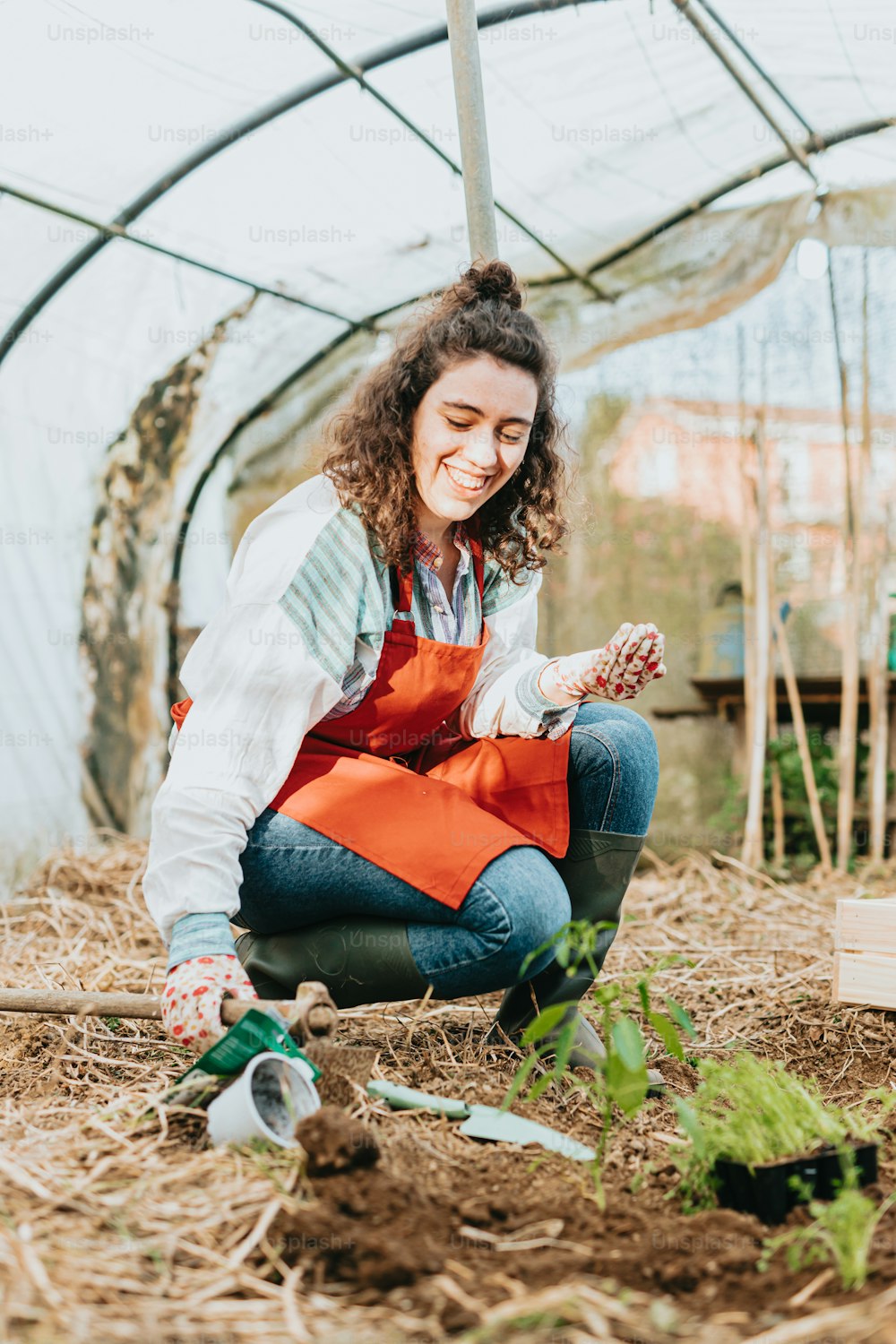 Una mujer arrodillada en un jardín sosteniendo una zanahoria