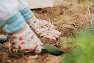 Una persona con guantes de jardinería al cavar en la tierra