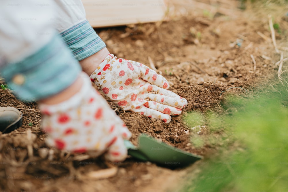 Una persona con guantes de jardinería al cavar en la tierra