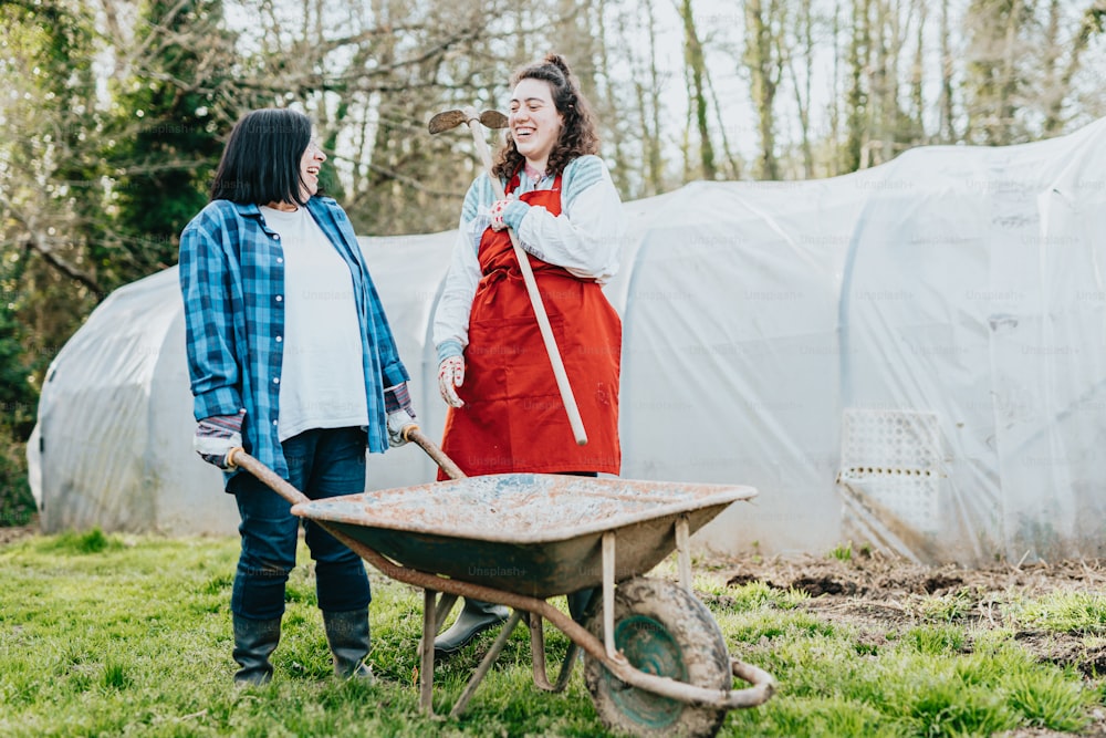 a couple of women standing next to a wheelbarrow