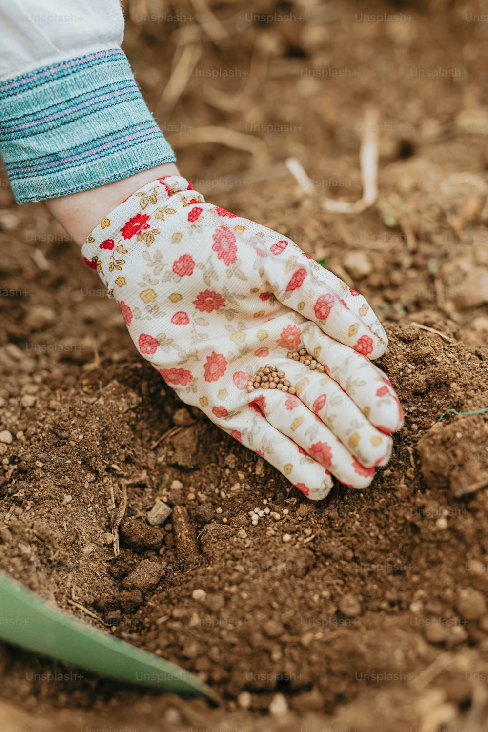 a person's hand with a glove on top of dirt