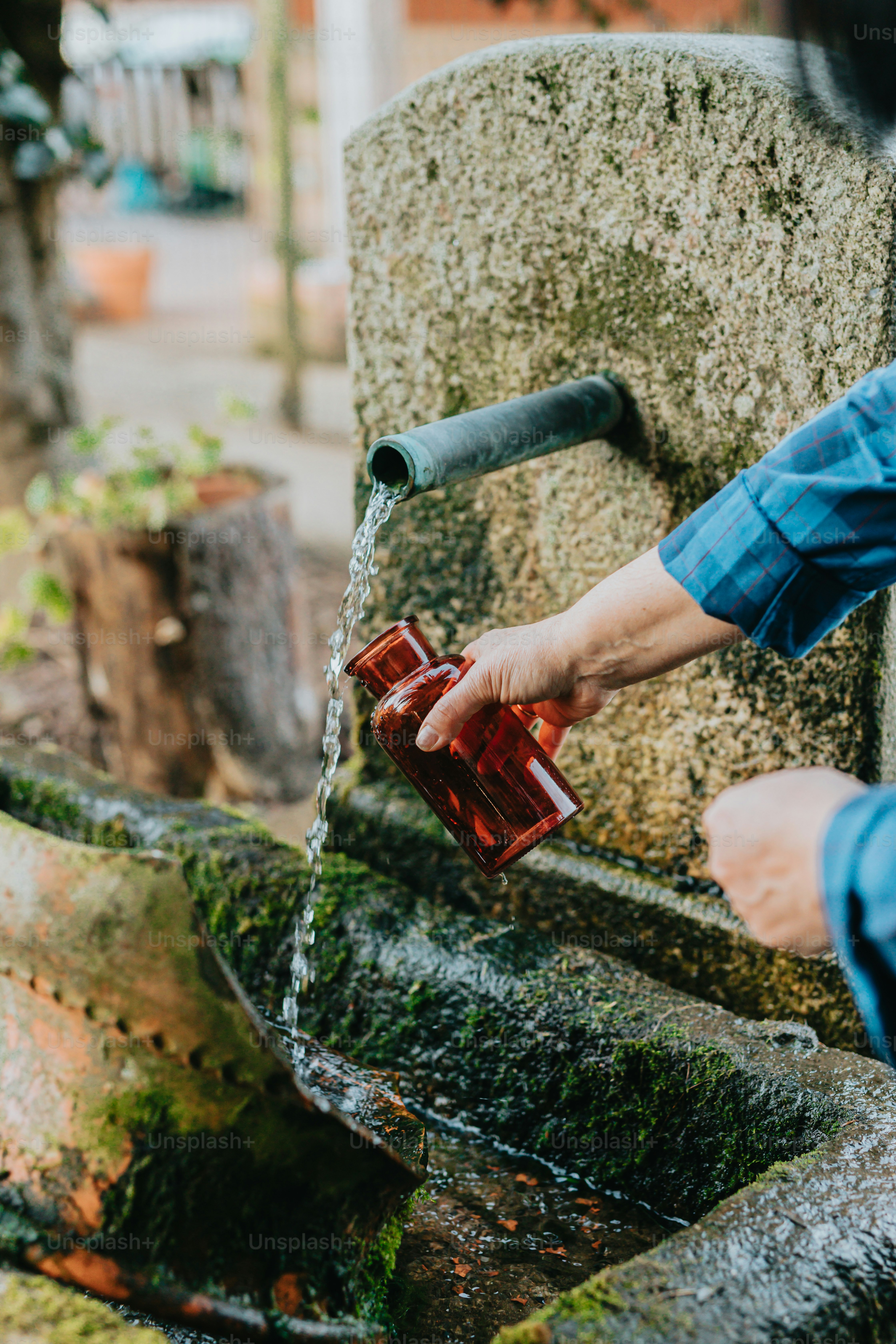 Una persona che versa acqua da un rubinetto in una tazza rossa