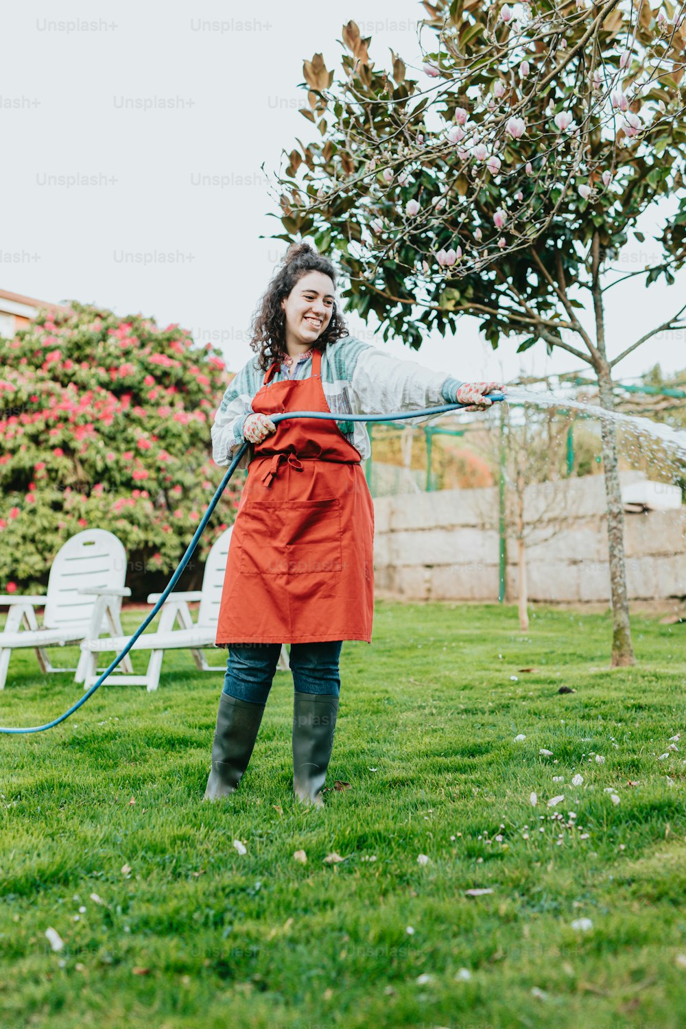 a woman in an orange apron is holding a hose