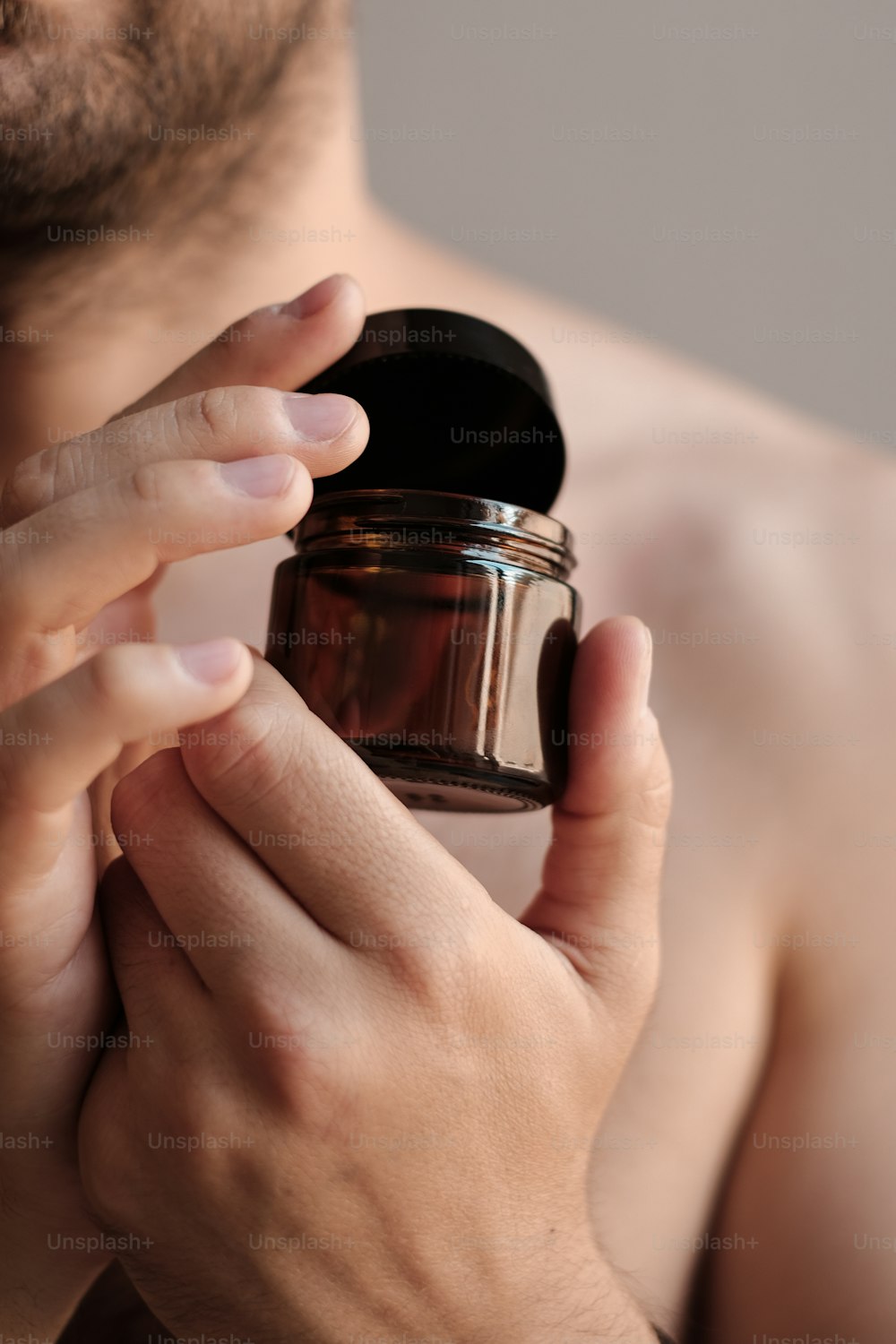 a shirtless man holding a jar in his hands