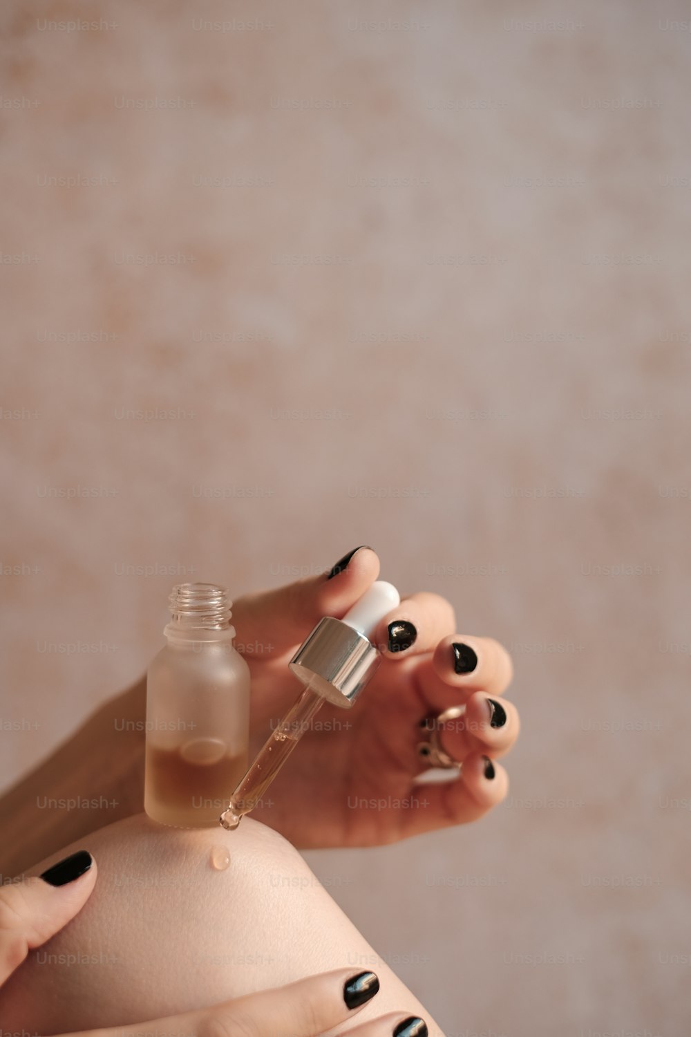 Une femme tenant une bouteille de vernis à ongles à côté d’une bouteille de liquide
