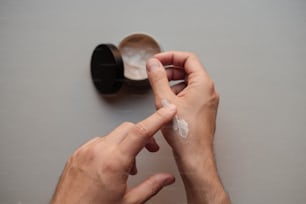 Un hombre se está poniendo una crema en la mano