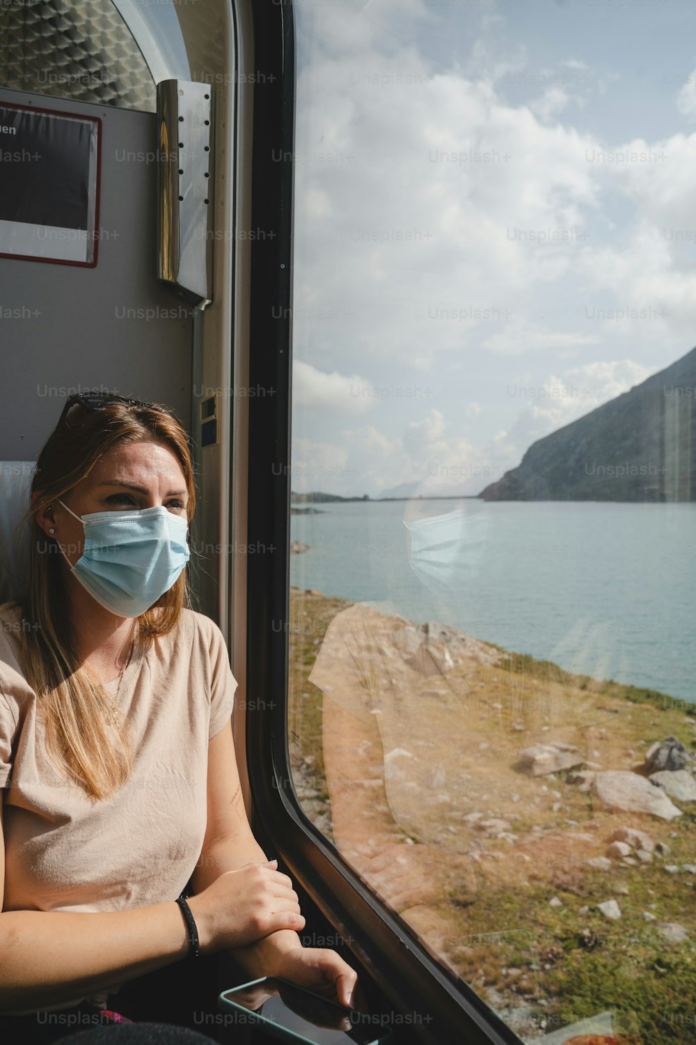 Une femme portant un masque facial regardant par la fenêtre d’un train