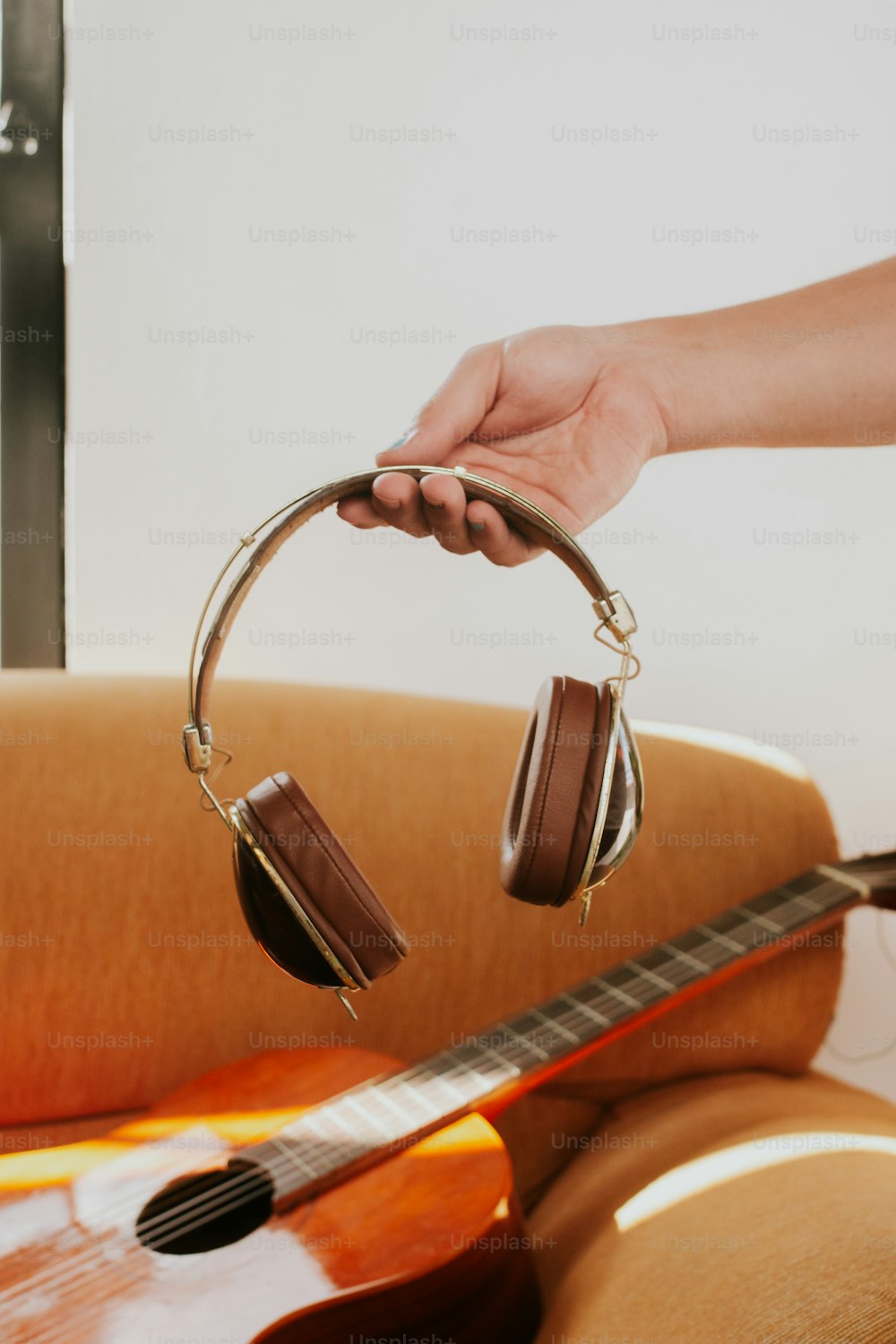 a person holding a pair of headphones in front of a guitar