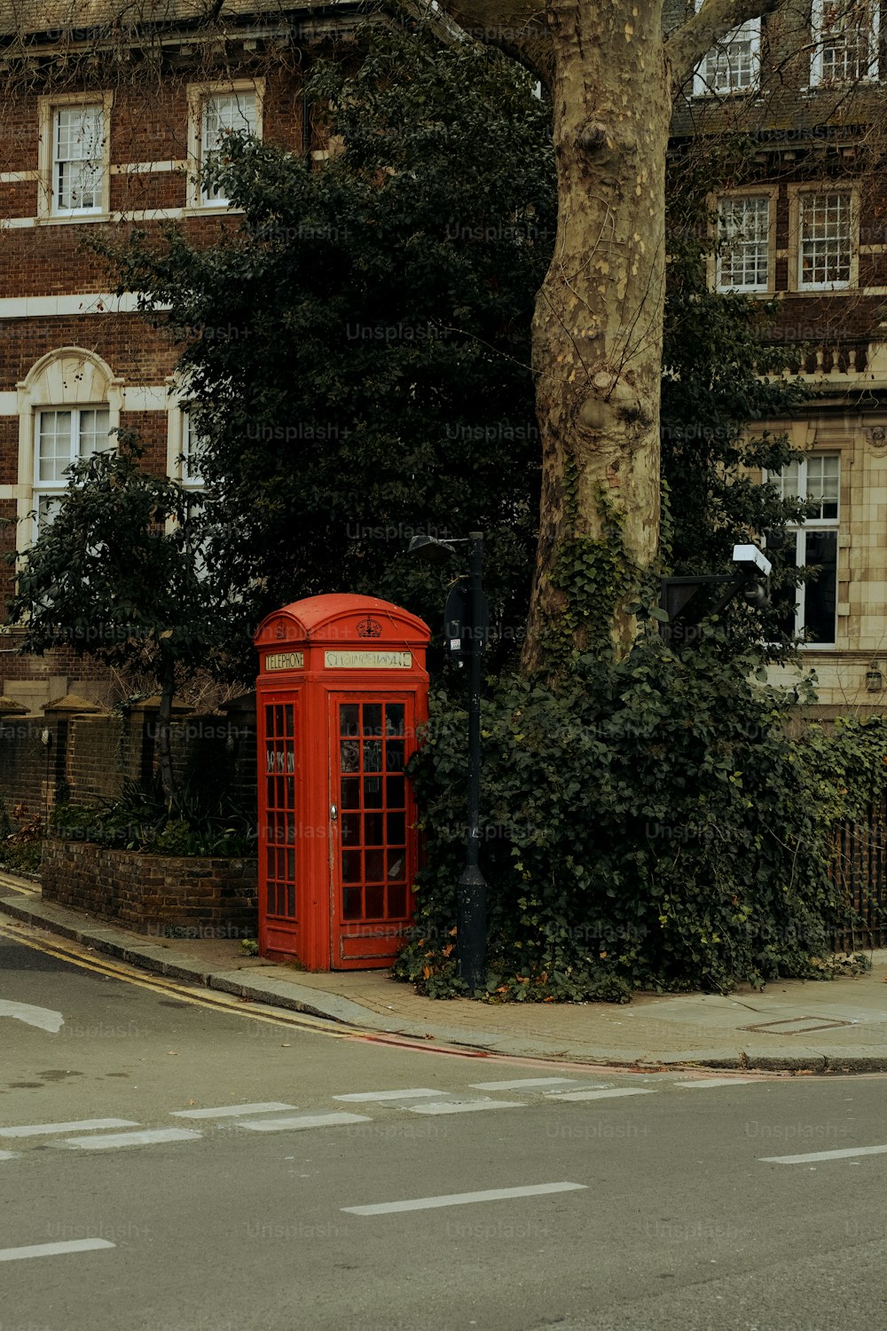 a red phone booth sitting on the side of a road