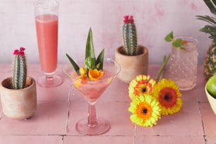 Una mesa rosa cubierta con tres vasos llenos de bebidas