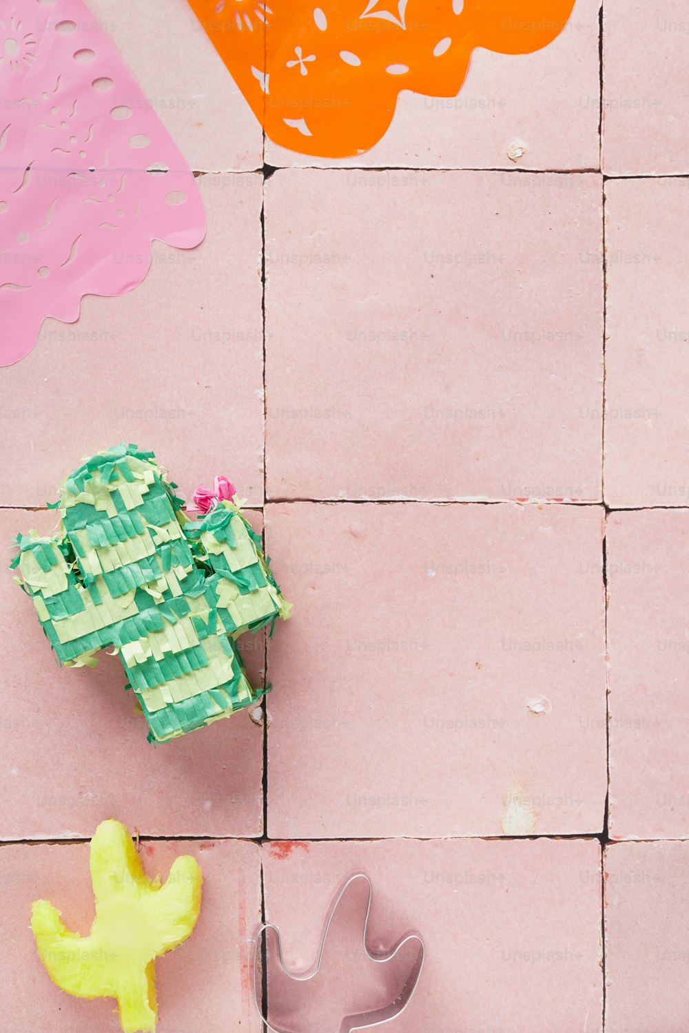 um piso de azulejos rosa com um cacto e um cortador de bolo