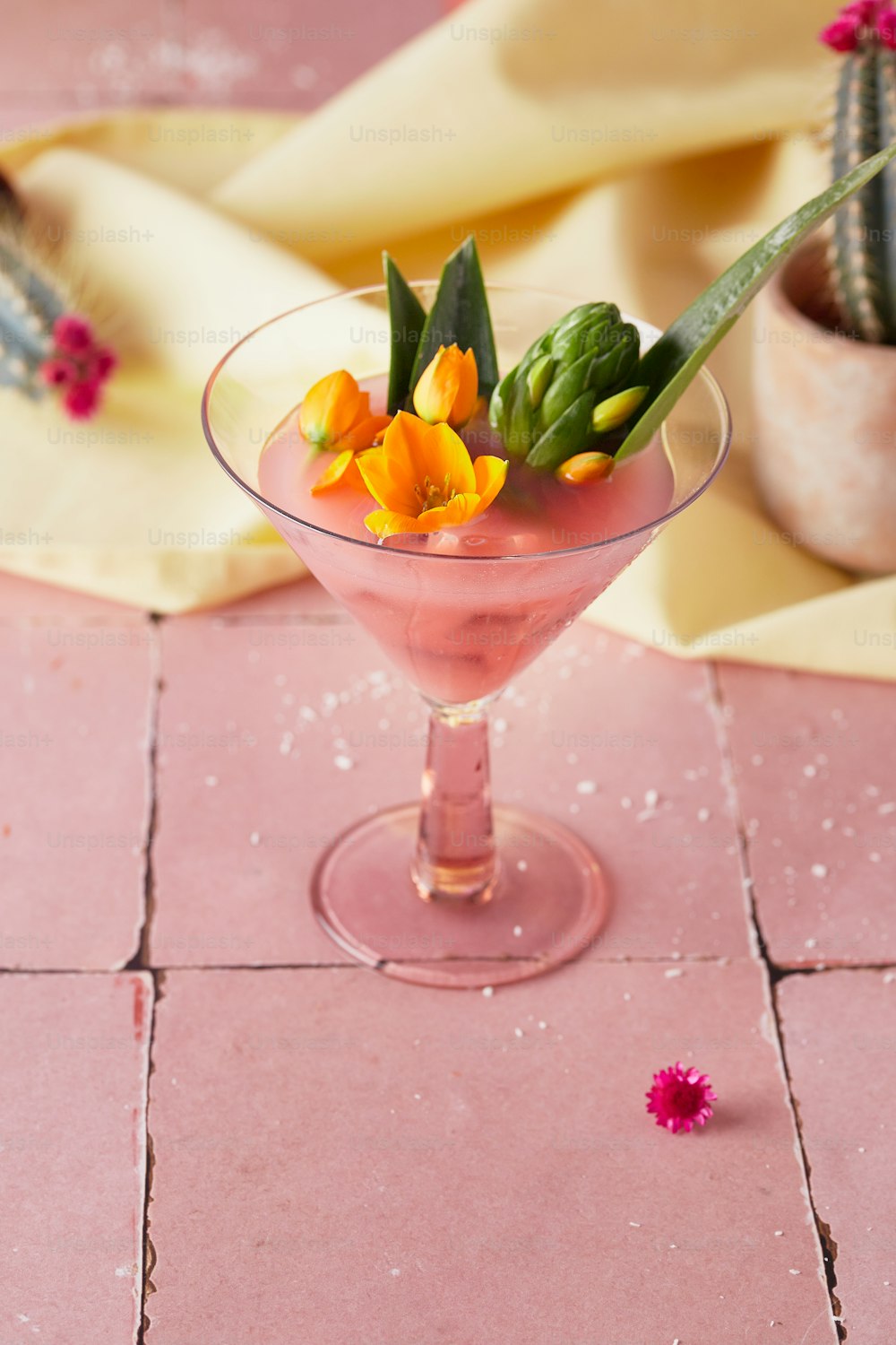 a pink cocktail with flowers in a glass