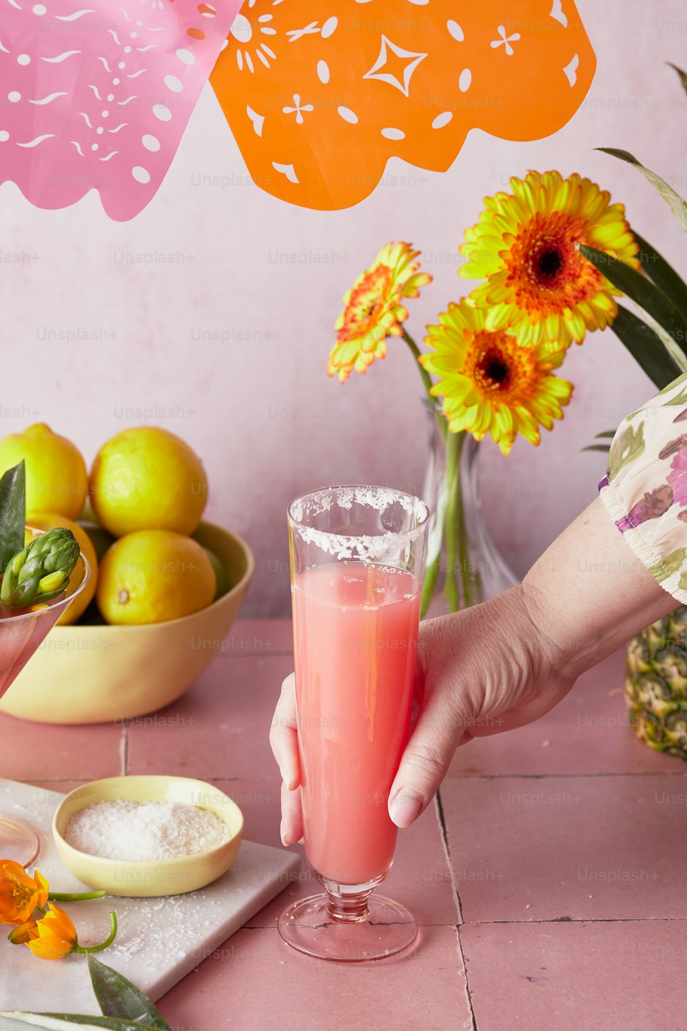 a person holding a glass of pink liquid