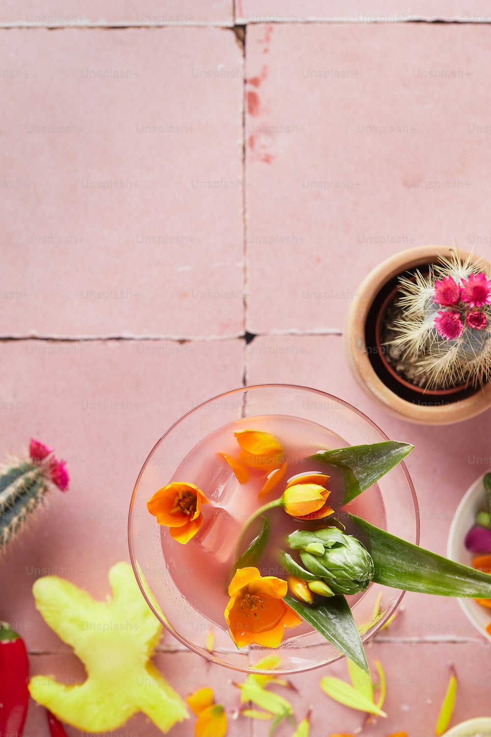 uma mesa rosa coberta com um copo cheio de flores